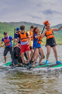 Grupo divirtiéndose con la tabla gigante King SUP de paddle surf