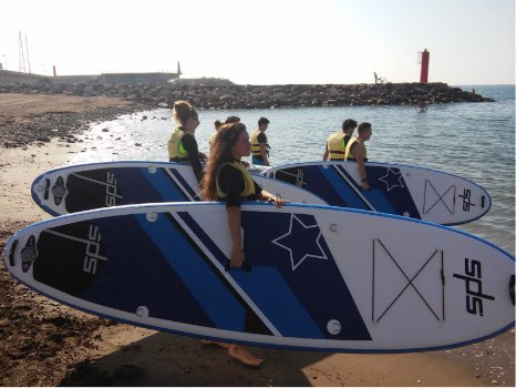 jóvenes entrando al agua con tablas de paddle surf de SPS