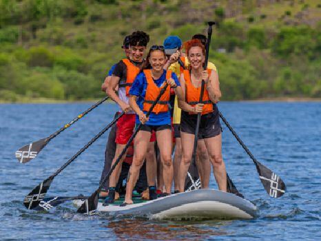 Adultos divirtiéndose en la tabla gigante King SUP de paddle surf