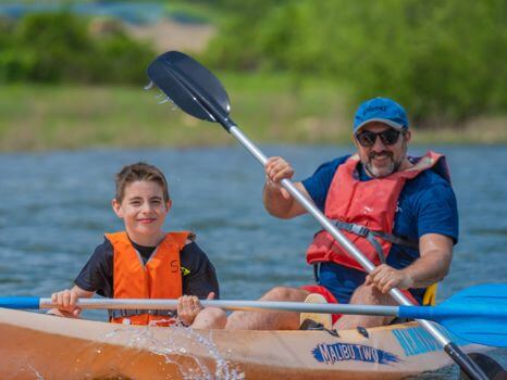 dos niños en el kayak realizando actividad de piragua en el embalse de Pinilla